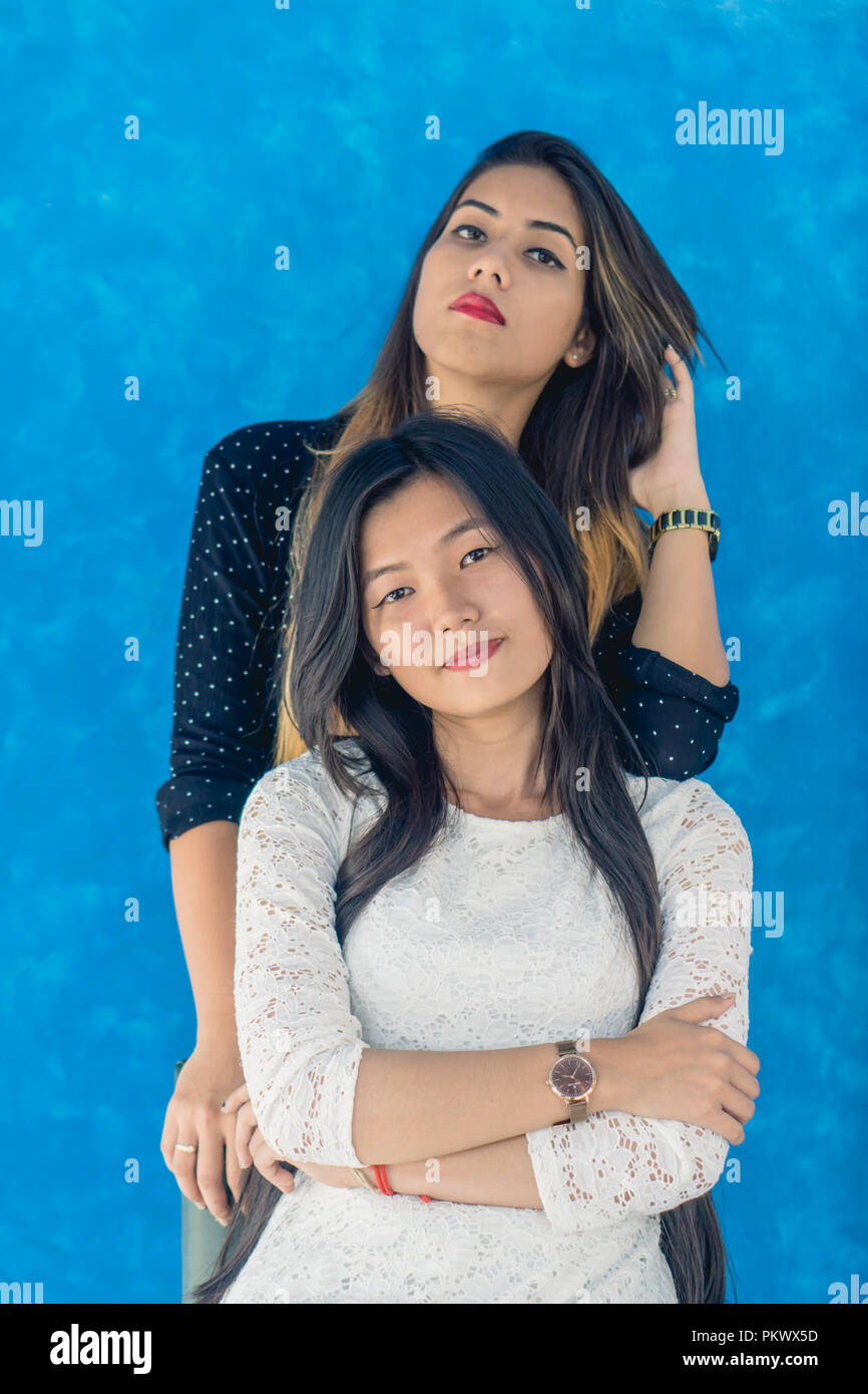 Two young girl posing for the camera against a blue background. Stock Photo
