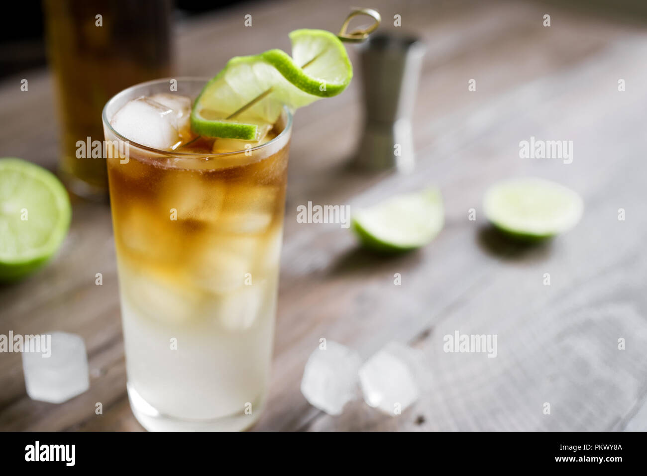 Dark and Stormy Rum Cocktail with Ginger Beer and Lime garnish. Glass of Dark and Stormy Cocktail drink on wooden table, copy space. Stock Photo