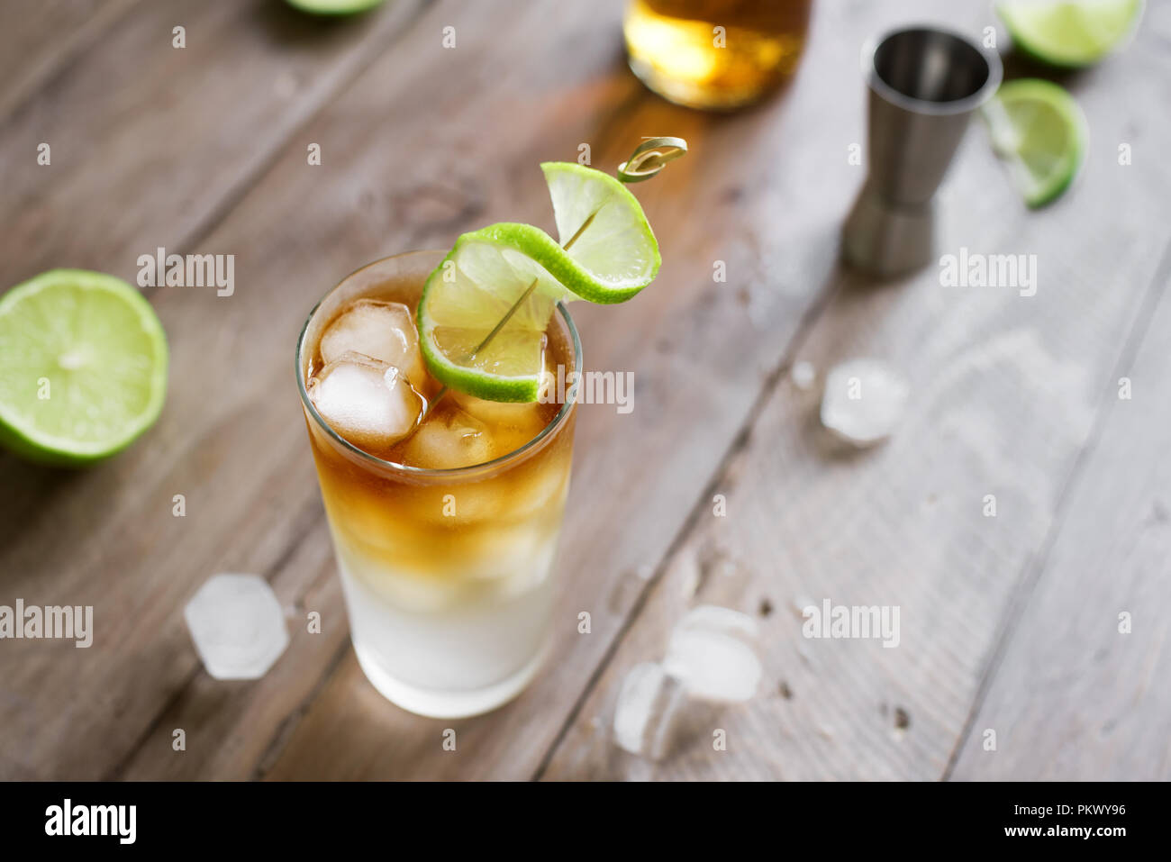 Dark and Stormy Rum Cocktail with Ginger Beer and Lime garnish. Glass of Dark and Stormy Cocktail drink on wooden table, copy space. Stock Photo