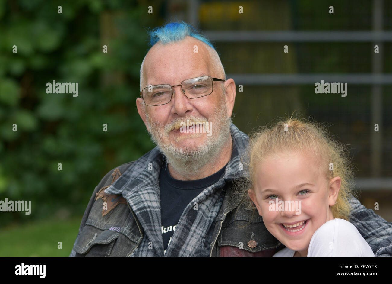 Grandfather with a blue mohawk with his young granddaughter Stock Photo
