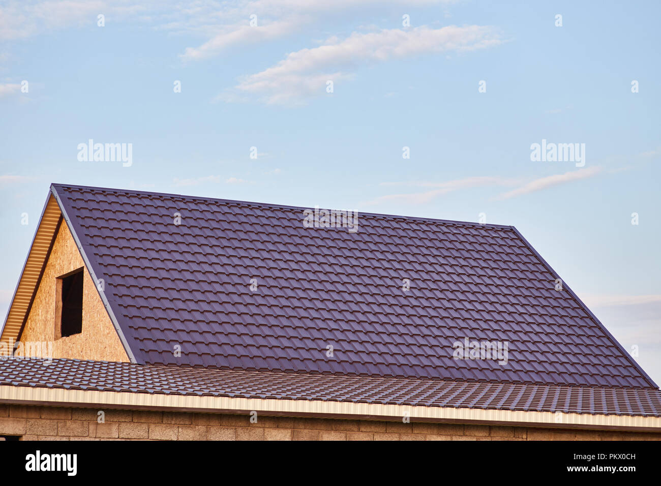 The roof of the house is covered with burgundy metal tile Stock Photo