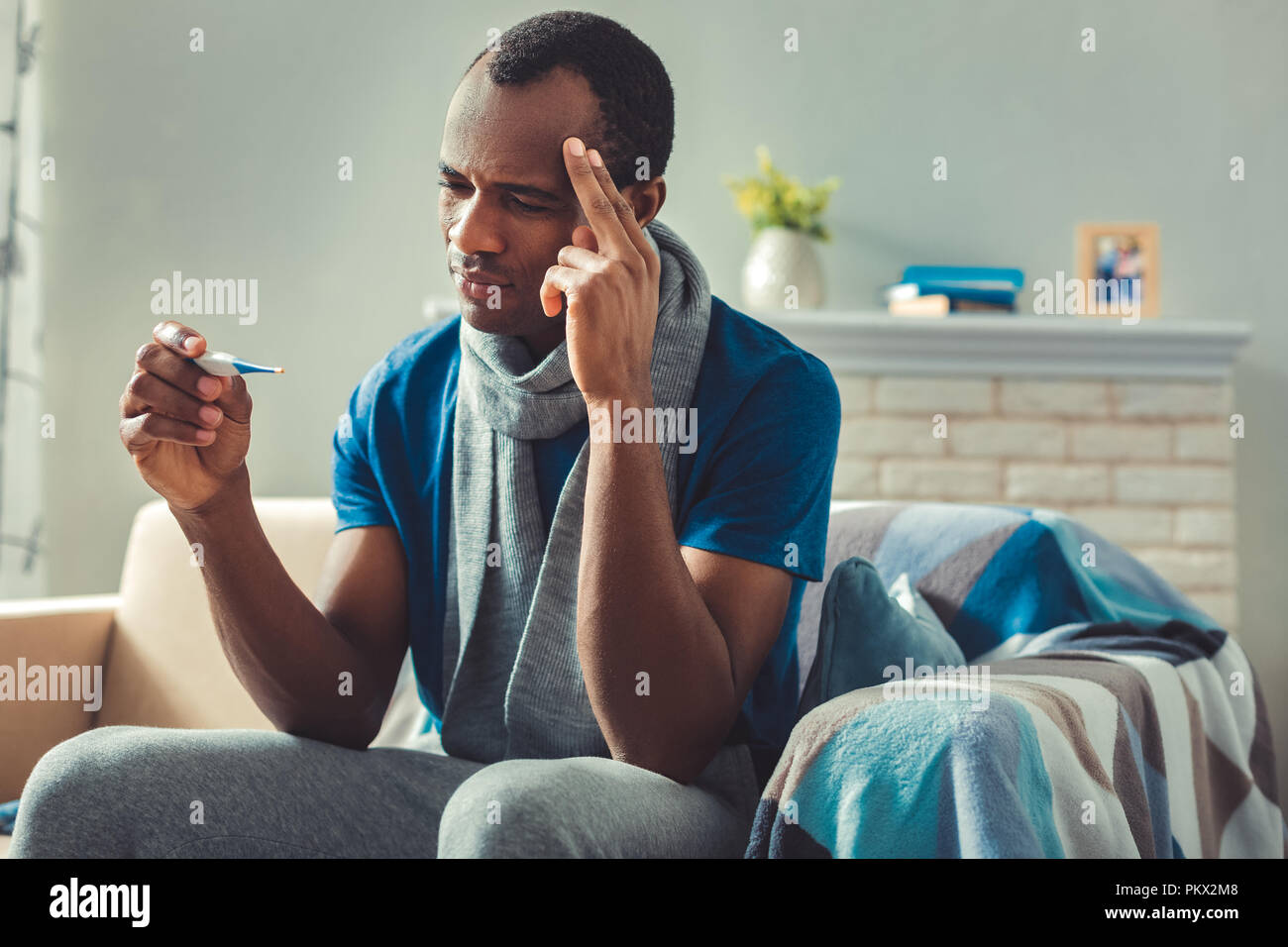Sad adult afro american man controlling temperature Stock Photo