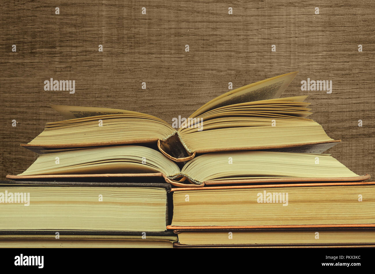 Stack of books on wooden background. many books piles. two opened books ...