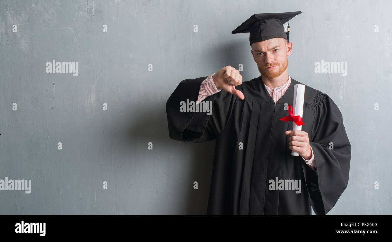 Young redhead man over grey grunge wall wearing graduate uniform ...