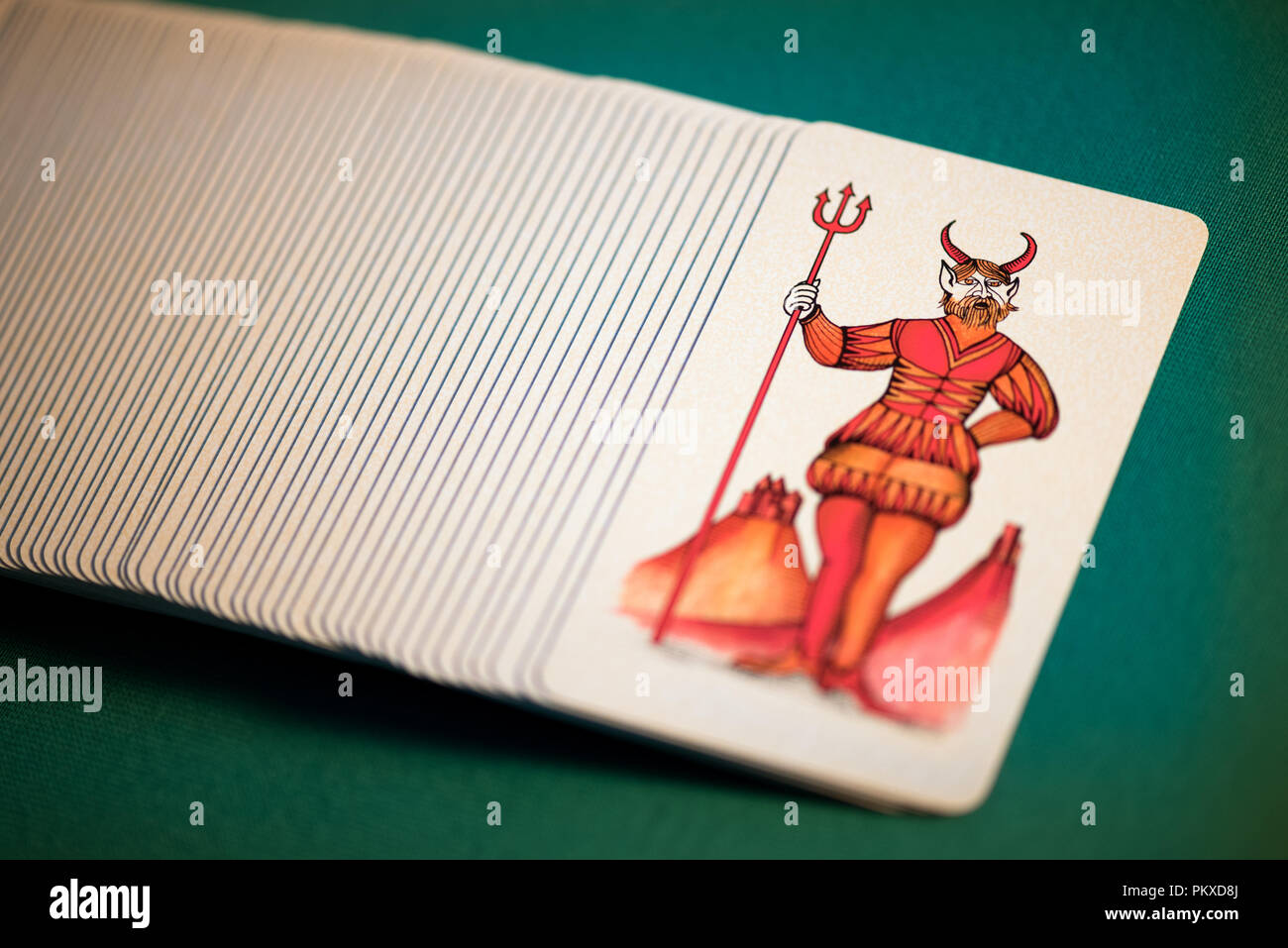 Pack of symbolic pictorial Tarot cards with the Devil or Satan uppermost spread out over a green background viewed close up high angle Stock Photo