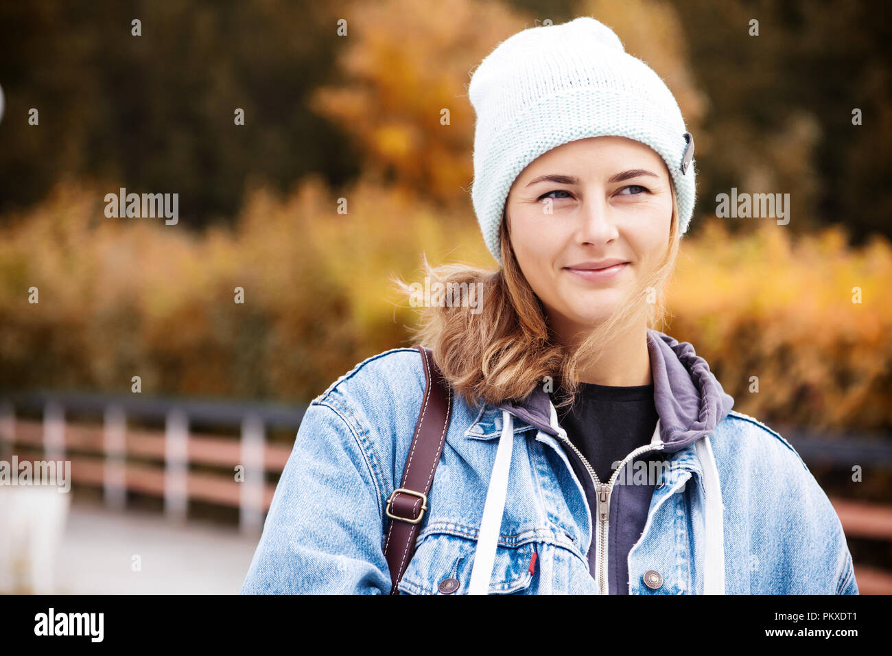 Gorgeous darkhaired woman wearing blue knitted hat and denim coat, posing on the background of lighthouse Stock Photo