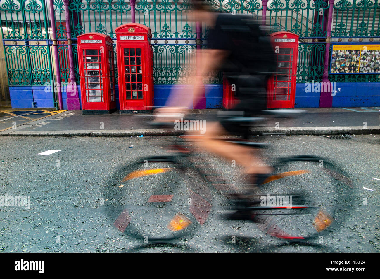 Iconic telephone boxes in an iconic location in the City of London with a blurred cyclist passing by Stock Photo