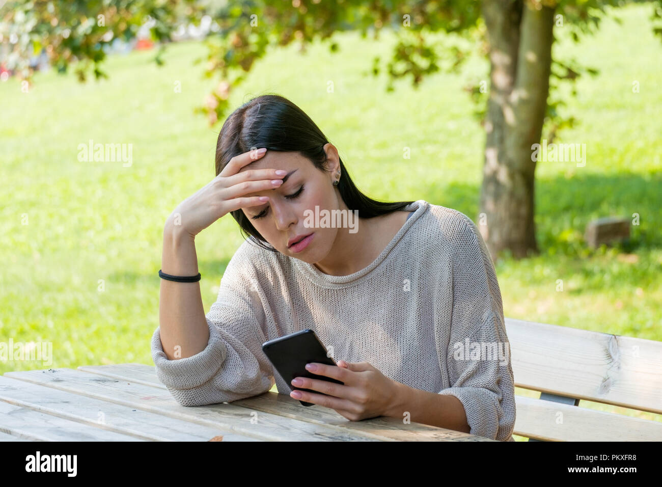 Sad girl watching her smartphone and feeling alone waiting social notifications Stock Photo