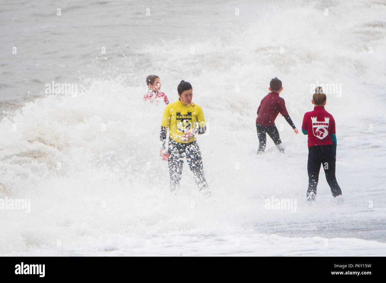 Aberystwyth, Wales, UK. 16 September 2018  UK Weather:  Young members of the local life saving club still train exuberantly in the waves on a wet and windy September Sunday afternoon. The west of the UK is bracing itself for the impact of Storm Helene, which is predicted to strike overnight on Monday, with winds gusting up to 70mph in exposed areas, , with the risk of danger to life from flying debris   Photo © Keith Morris / / Alamy Live News Stock Photo