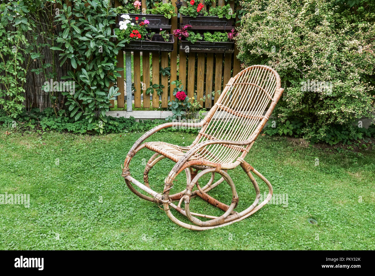 Still life with the old wicker rocking chair in the garden Stock Photo