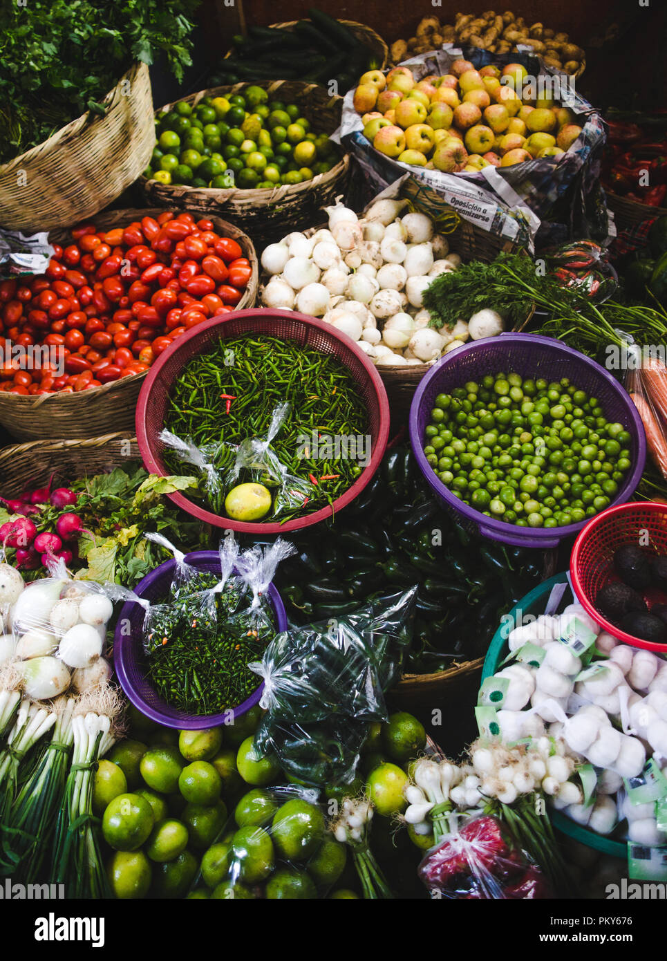 Autumn harvest of fresh organic vegetables on sale at a market stall - colorful bowls of tomato, beans, chillies, garlic, mushrooms, limes and apples Stock Photo