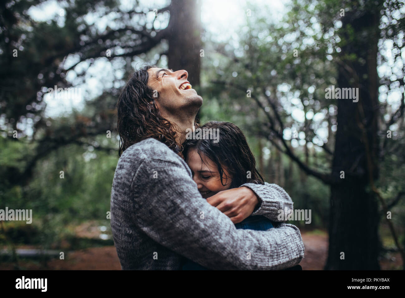 Couple in love embracing in the park under rain. Smiling young man ...