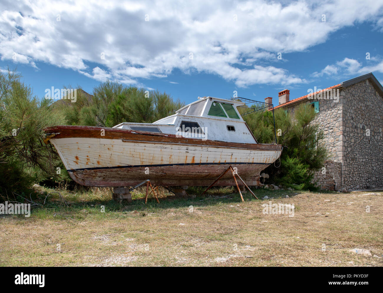 Abandoned boat on shore stone house in background Stock Photo - Alamy