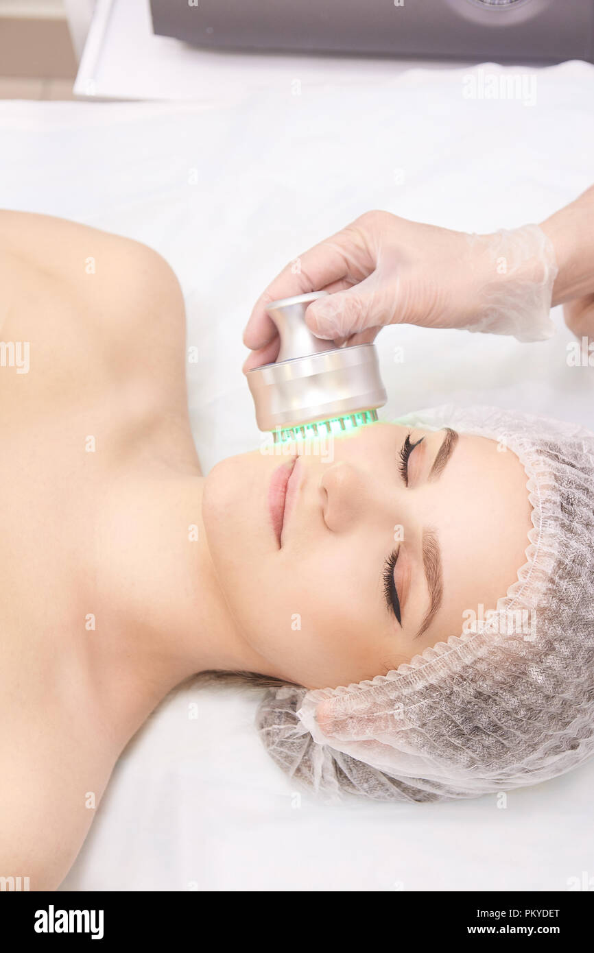 Woman cosmetology procedure. Light face treatment. Medical skin repair. Anti wrinkle. Color skincare. Stock Photo