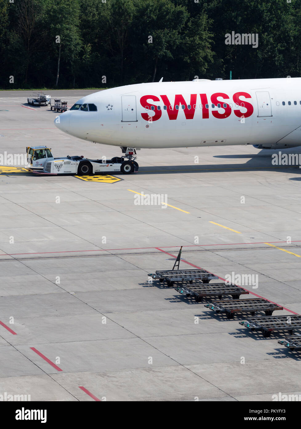 An aircraft tug is pulling an Airbus A340 of Swiss International Air Lines away from the gate at Zurich internation airport. Stock Photo