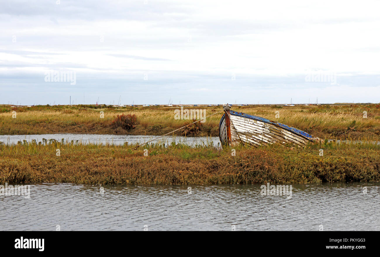 An old grounded clinker built boat by creeks in salt marshes on the North Norfolk coast at Morston, Norfolk, England, United Kingdom, Europe. Stock Photo