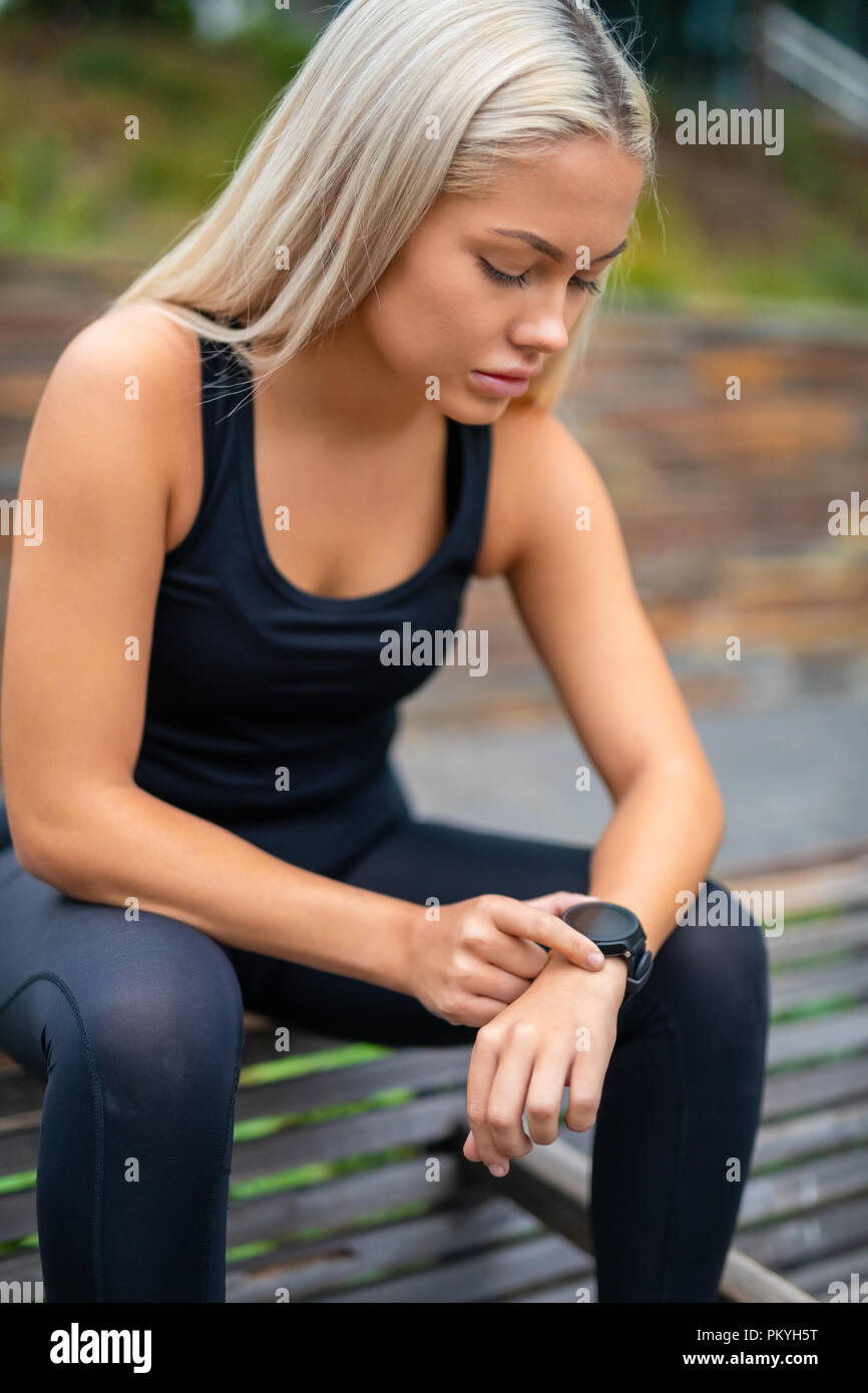Woman Taking A Break After Workout And Checking Time On Smartwat Stock Photo