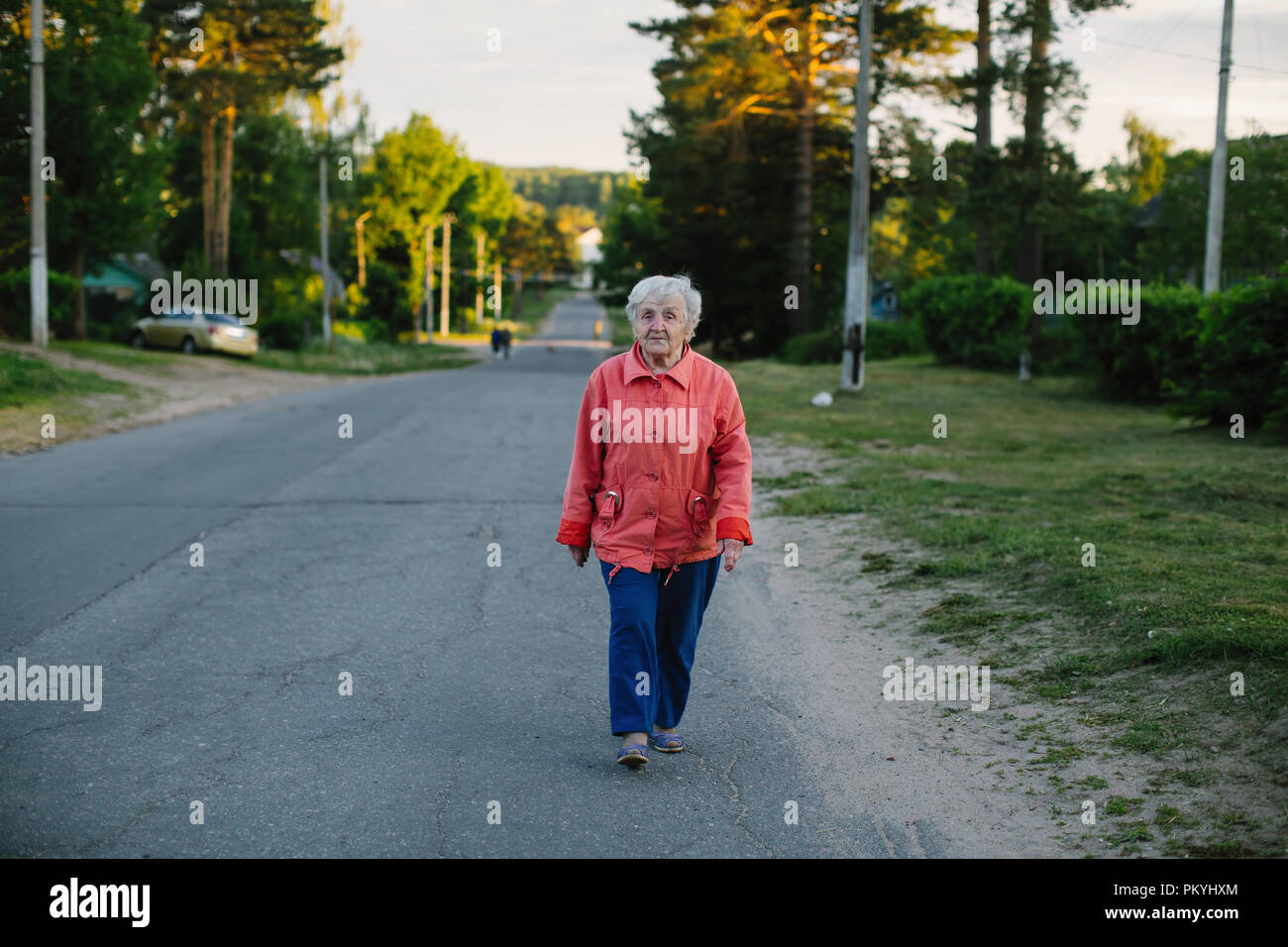 An elderly woman strolls through the village Stock Photo - Alamy