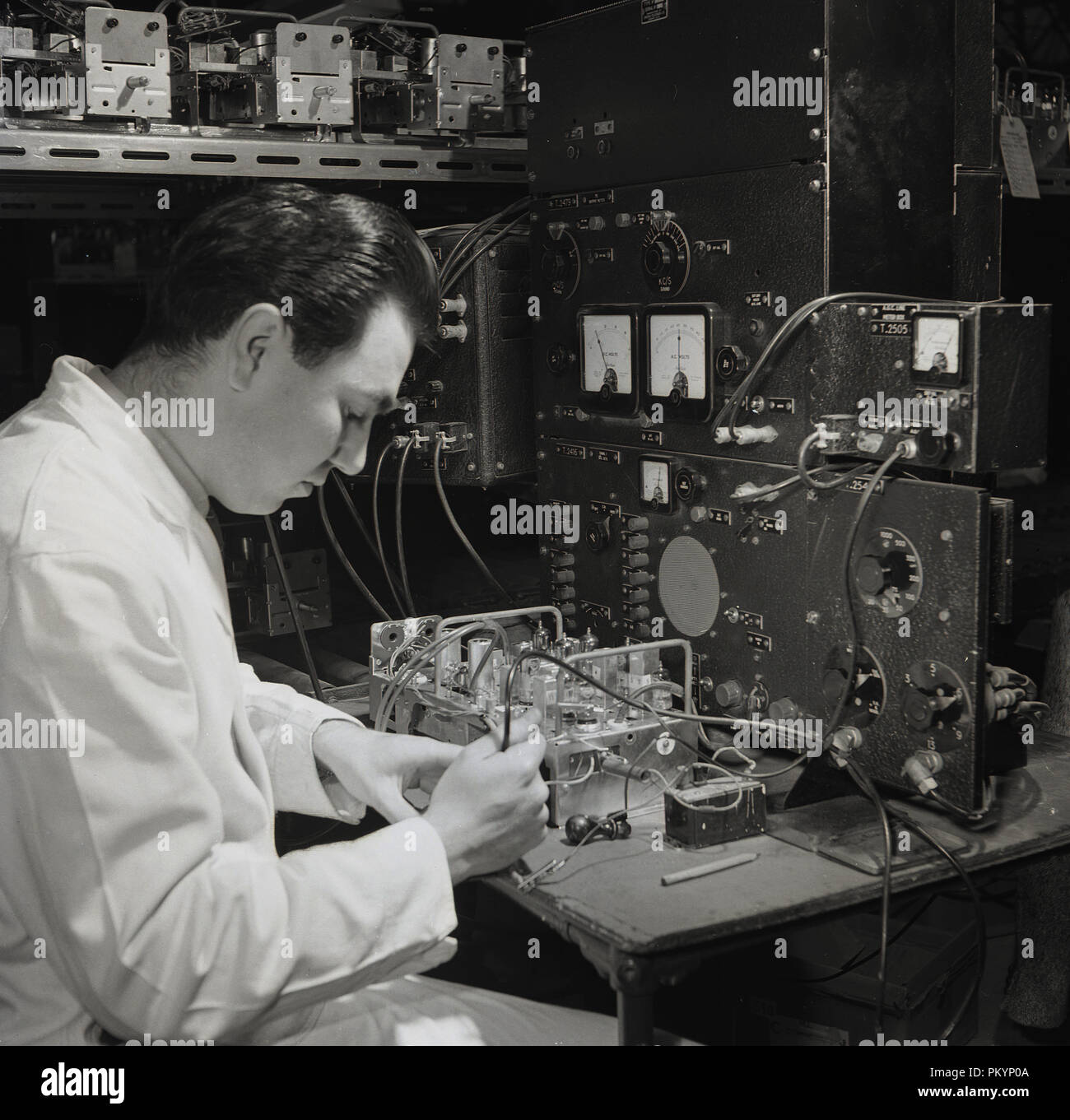 1950s, historical, a whitecoated male technican testing the internal components of a wireless