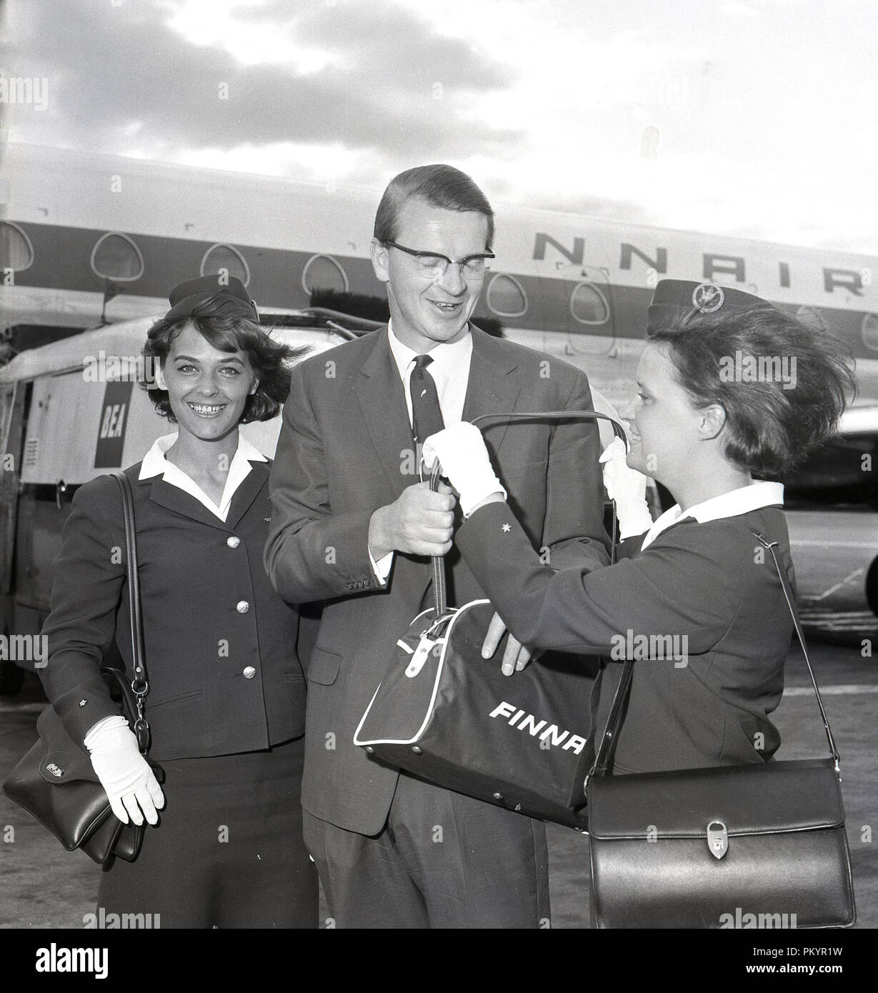 1960s, historical, a gentleman flying with Finland's national airline,  Finnair being given a gift of a small comany travel bag from one of the  aircraft's uniformed female flight attendants, London, England, UK