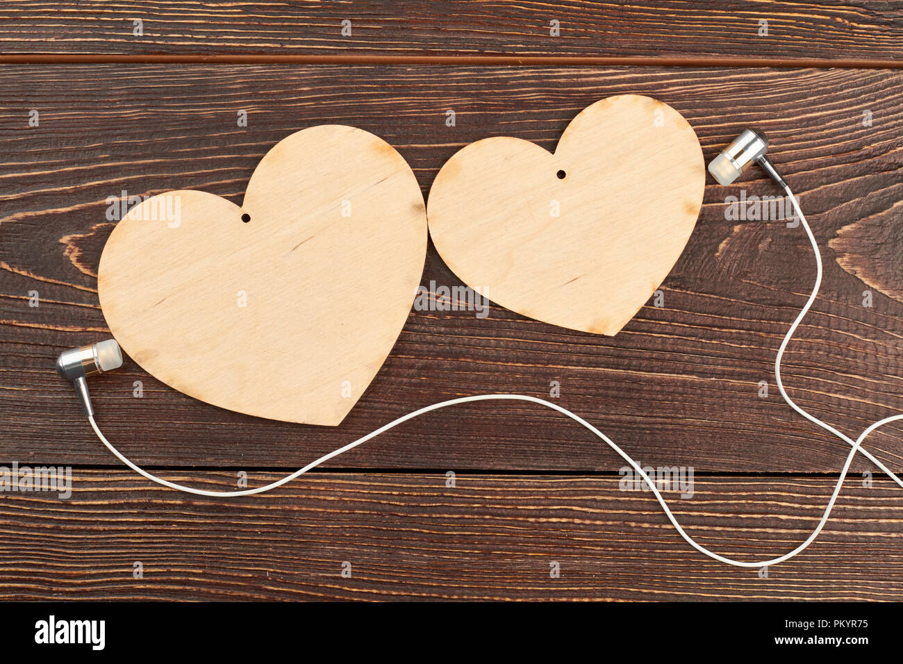 Carved hearts and earphones on wooden background. Blank hearts for decoupage and headphones. Music is love. Romantic music concept. Stock Photo