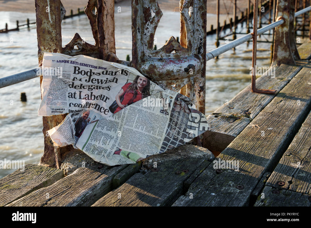 Windswept tabloid featuring an article about the Labour Party anti-antisemitism row stuck to the rusty side of an old jetty in Bognor Regis Stock Photo