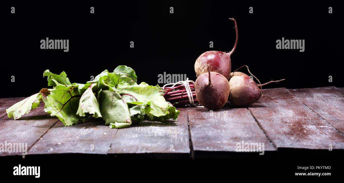 Red Beetroot with herbage green leaves on rustic background. Organic Beetroot. Stock Photo