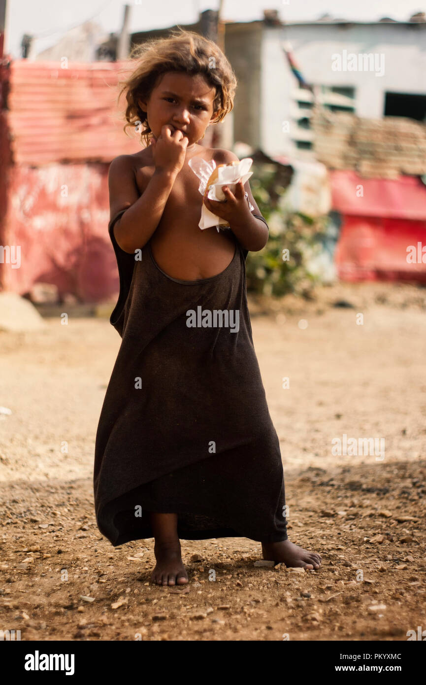 BARCELONA, VENEZUELA June 2, 2018: girl in the poor community 'ciudad de los mochos' wears an adult shirt as her only dress Stock Photo
