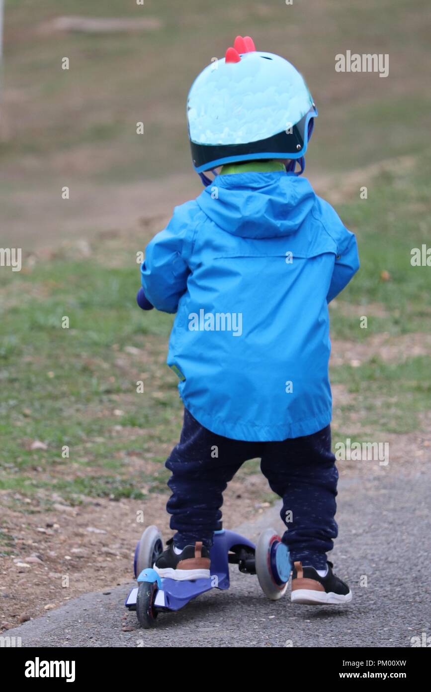 Infant child wrapped up warm ina coat wearing a safety helmet On a toy