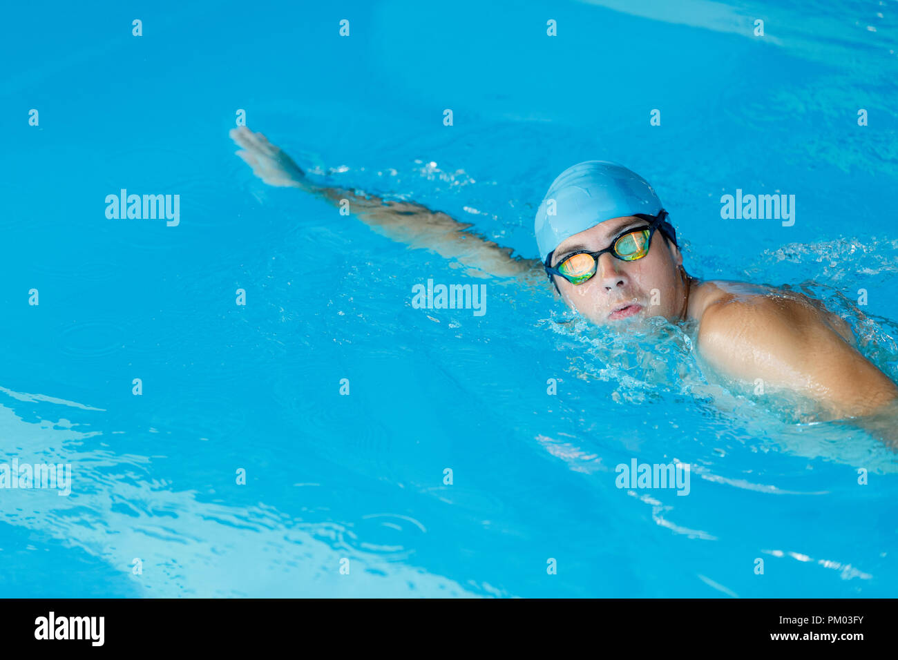 Portrait of sportive man in blue cap floating in pool Stock Photo