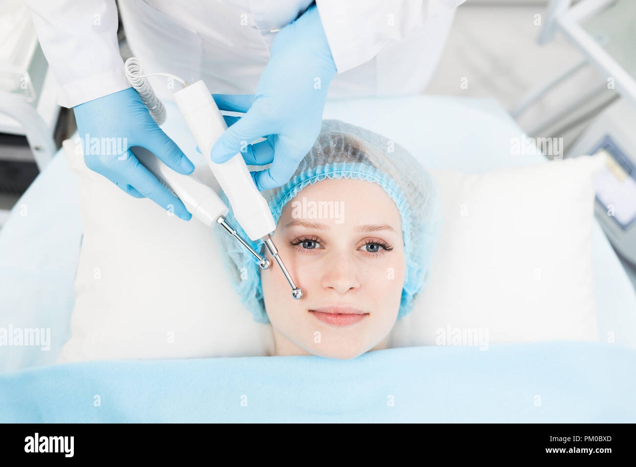 Gloved beautician making beauty procedure for facial care on client