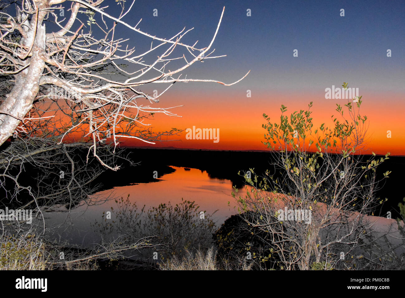 Serene sunset landscape with river in the foreground and golden skies at sunset. A serene setting ideal to enjoy a sun downer under African skies Stock Photo