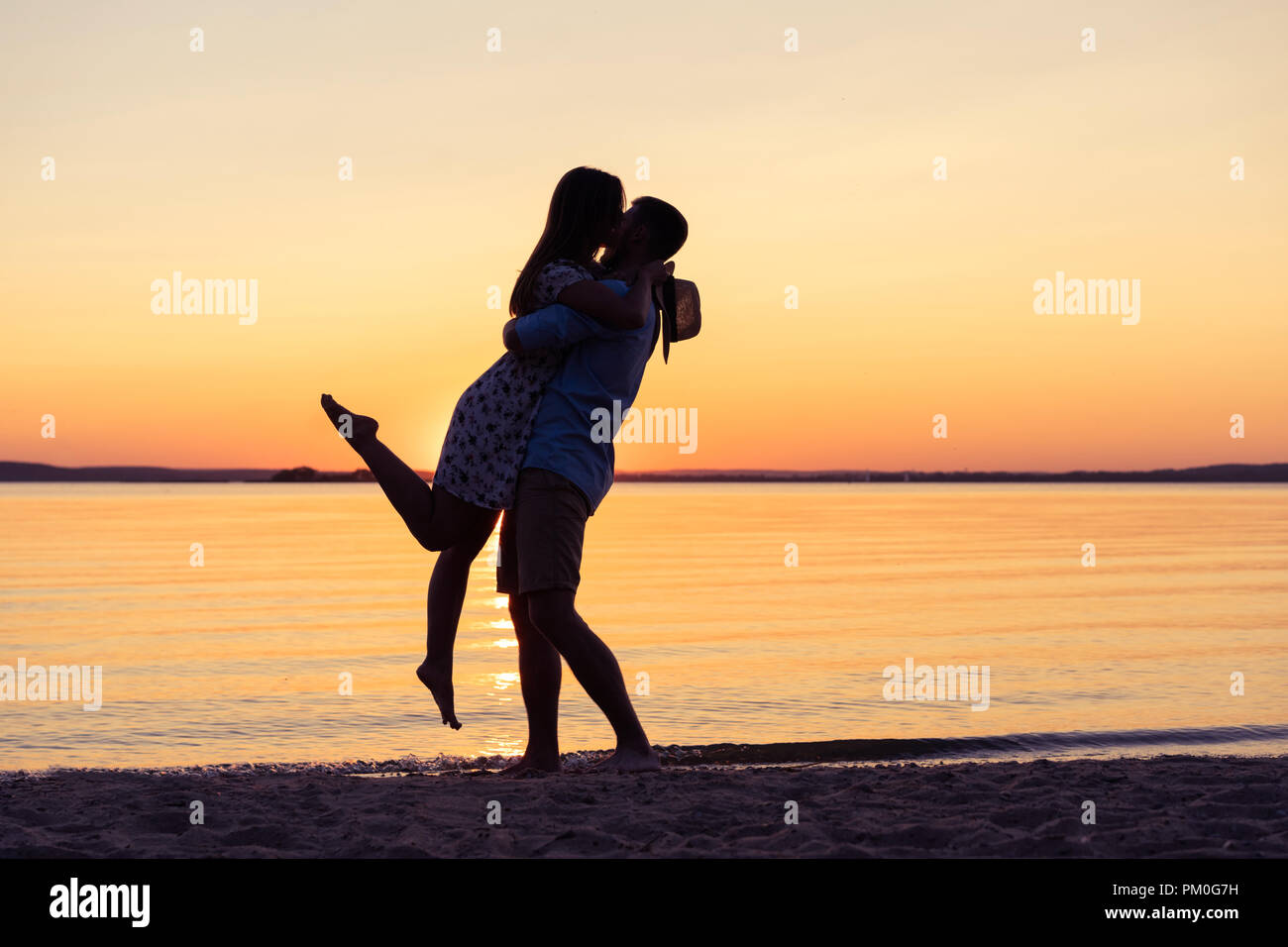 Silhouette Of Happy Couple On Beach At Sunset Man Taking The Girl In His Arms Stock Photo Alamy