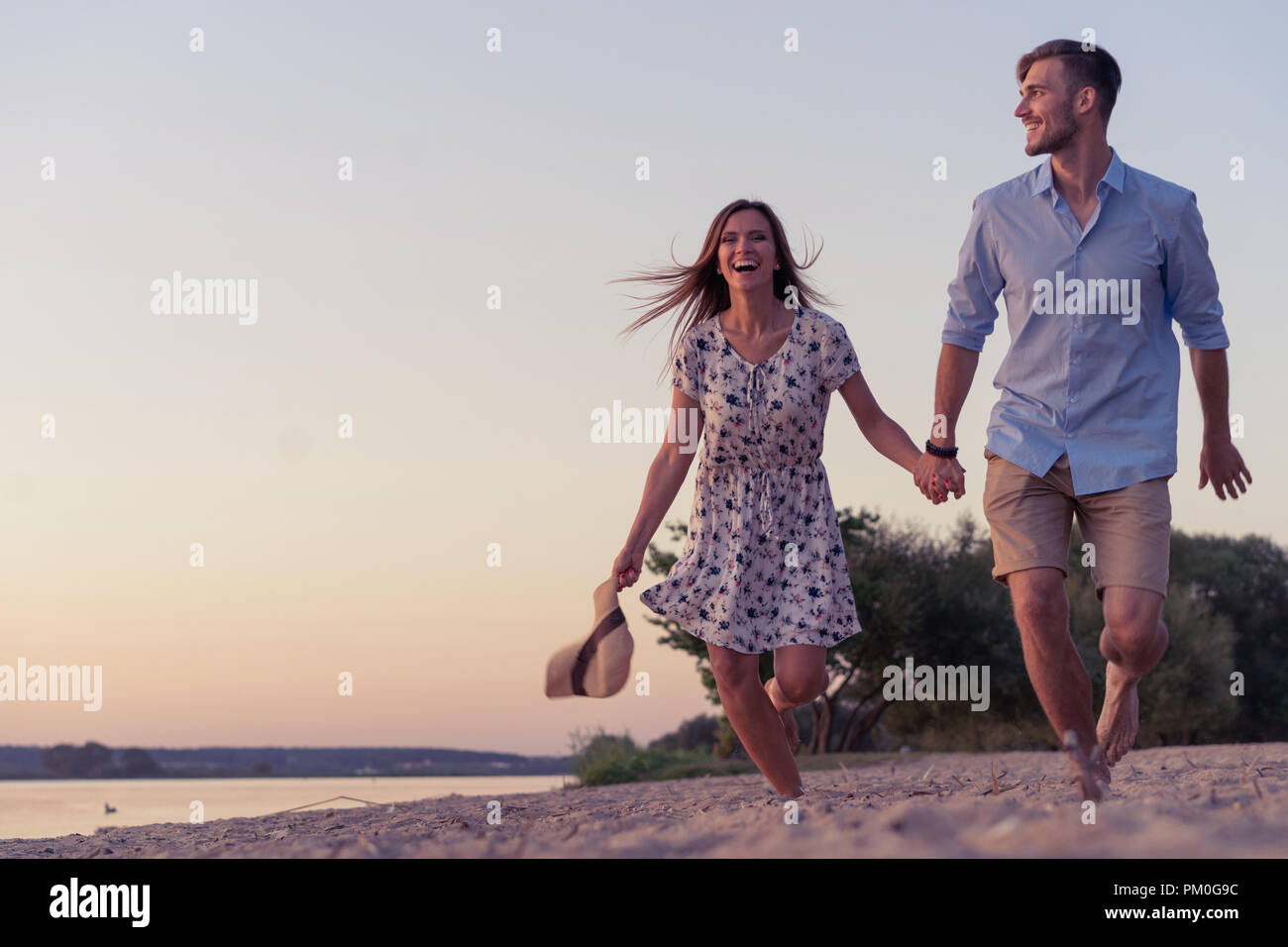 Couple walking on the beach at sunset Stock Photo - Alamy
