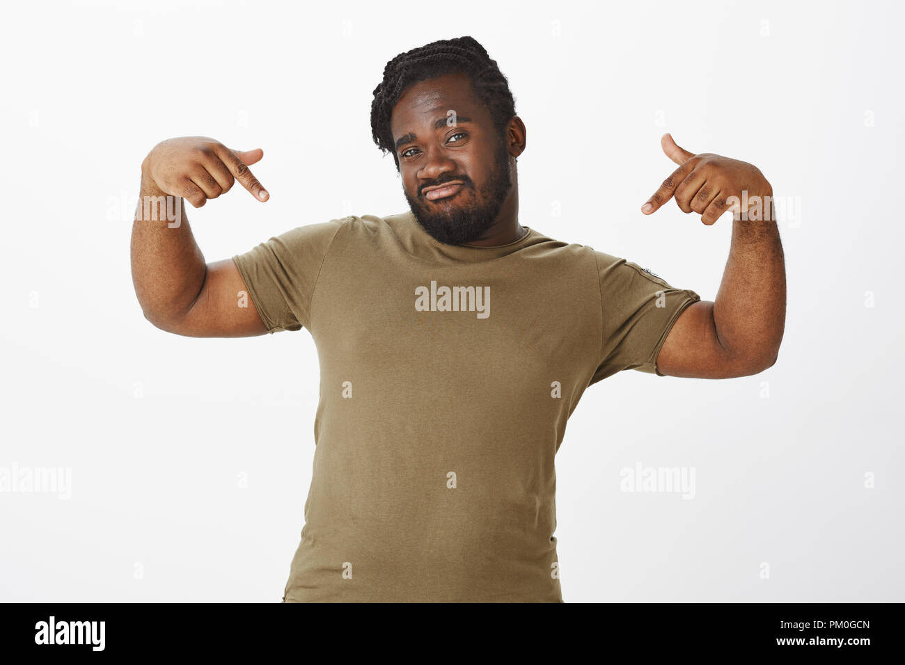 Look how cool I am. Confident good-looking plump african-american man, making not bad expression, raising index fingers and pointing at chest, talking about himself with self-assured attitude Stock Photo