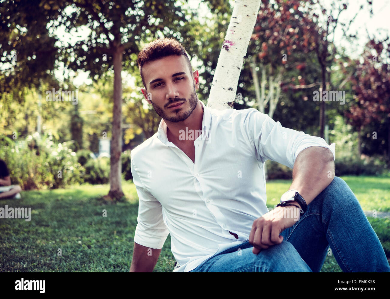 Attractive Handsome Young Man In City Park Sitting In A Summer