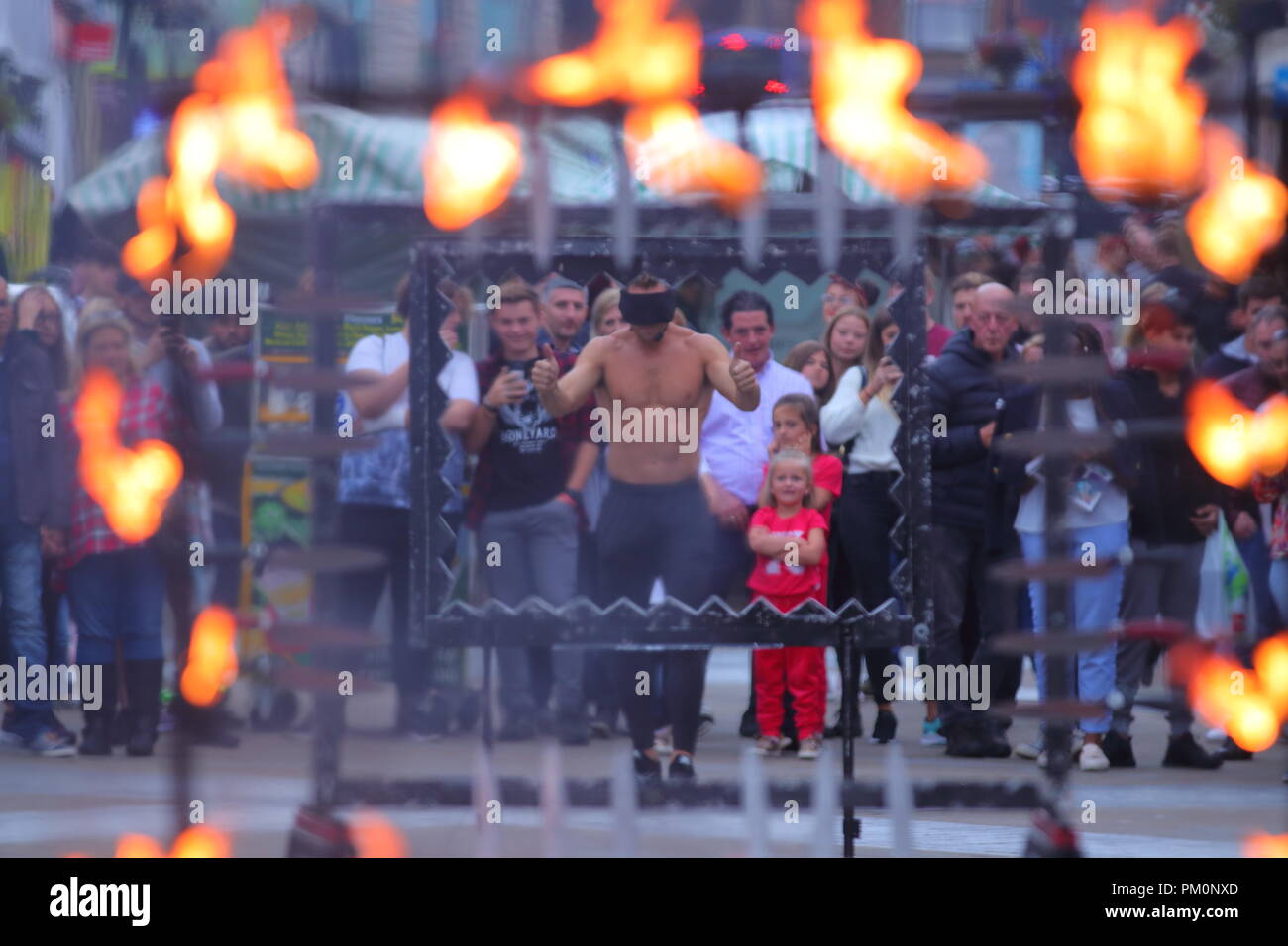 A dare devil throws his self through sharp knives & fire while  blindfolded as part of his street theatre act on Briggate, Leeds,West Yorkshire. Stock Photo