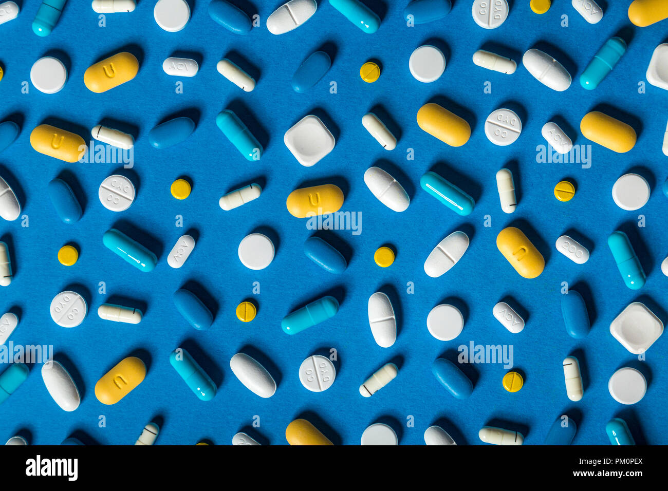 Scattered pills, capsules and tablets against blue background, supplements, medication, healthcare Stock Photo