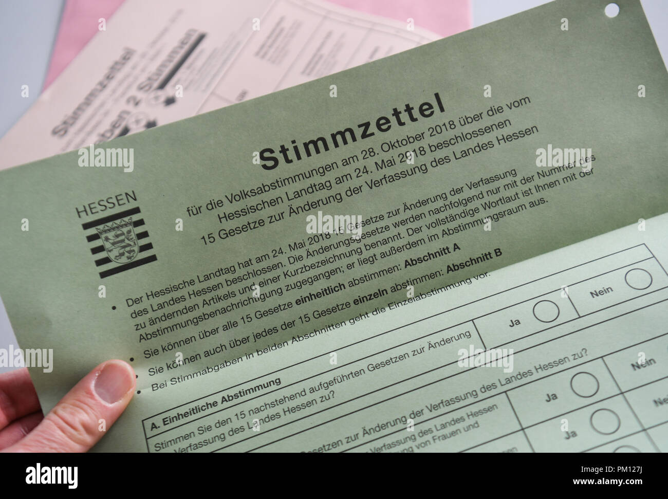 14 September 2018, Hessen, Frankfurt/Main: ILLUSTRATION - 14 September 2018, Germany, Frankfurt/Main: A hand holds a ballot paper for the referendum on amendments and supplements to the state constitution in the Frankfurt electoral office. About six weeks before the state elections in Hesse, particularly hasty voters will be able to cast their votes from 17 September 2018. From this day on, the documents are available for postal voting at the municipal electoral offices. (on dpa 'Voting on the Hessian state election begins with postal vote' of 16.09.2018) Photo: Arne Dedert/dpa Stock Photo