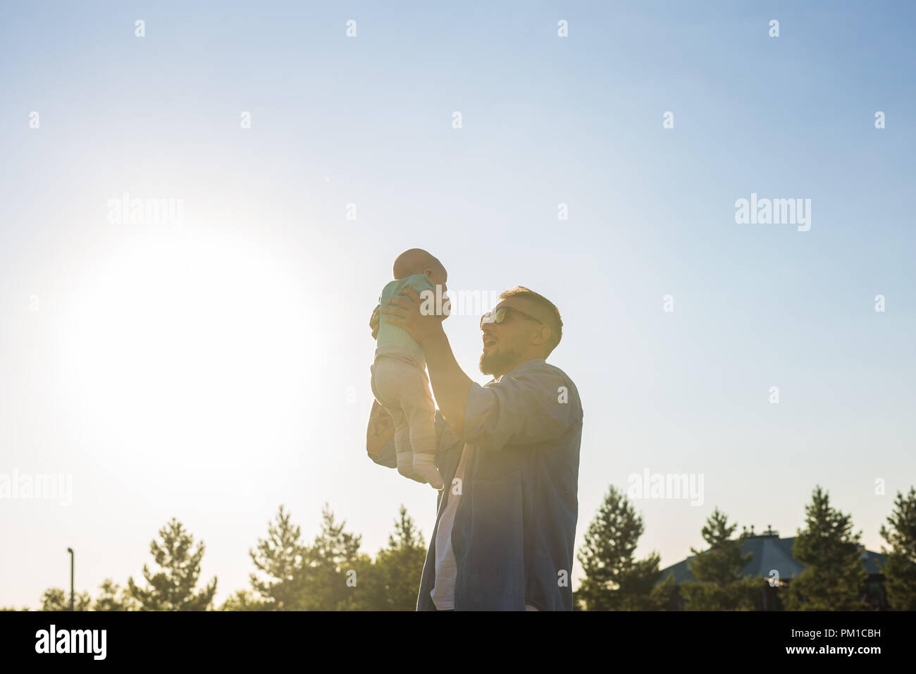 Happy father holding baby son, throwing baby in air. Concept of happy