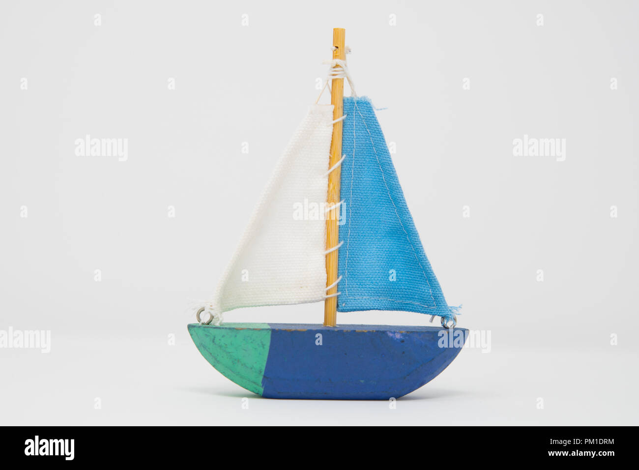 A wooden toy yacht. The toy boat shows signs of use, but the sails are