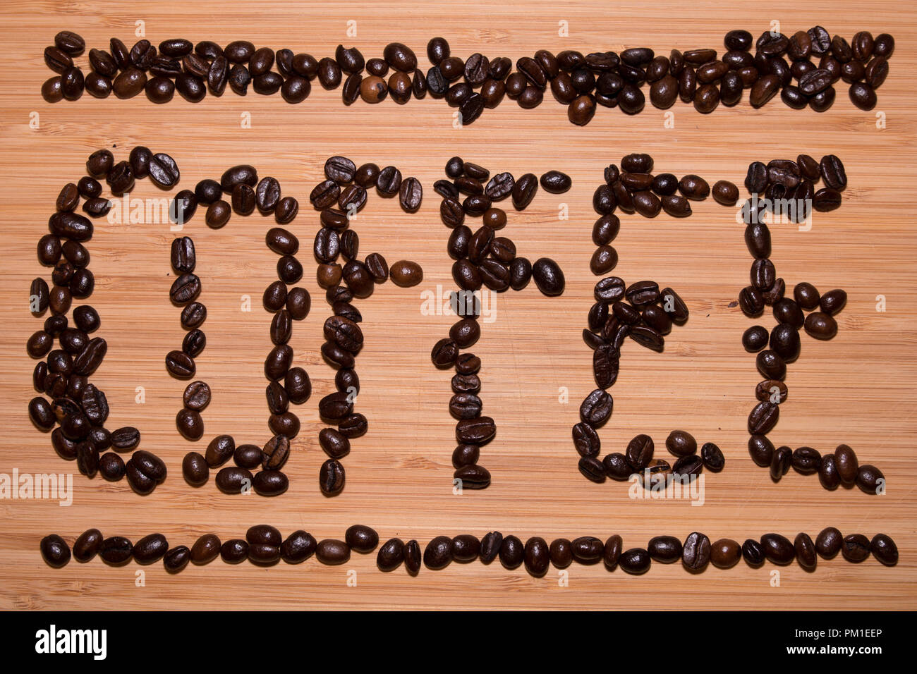 The word "Coffee" written out on a light wooden background formed from