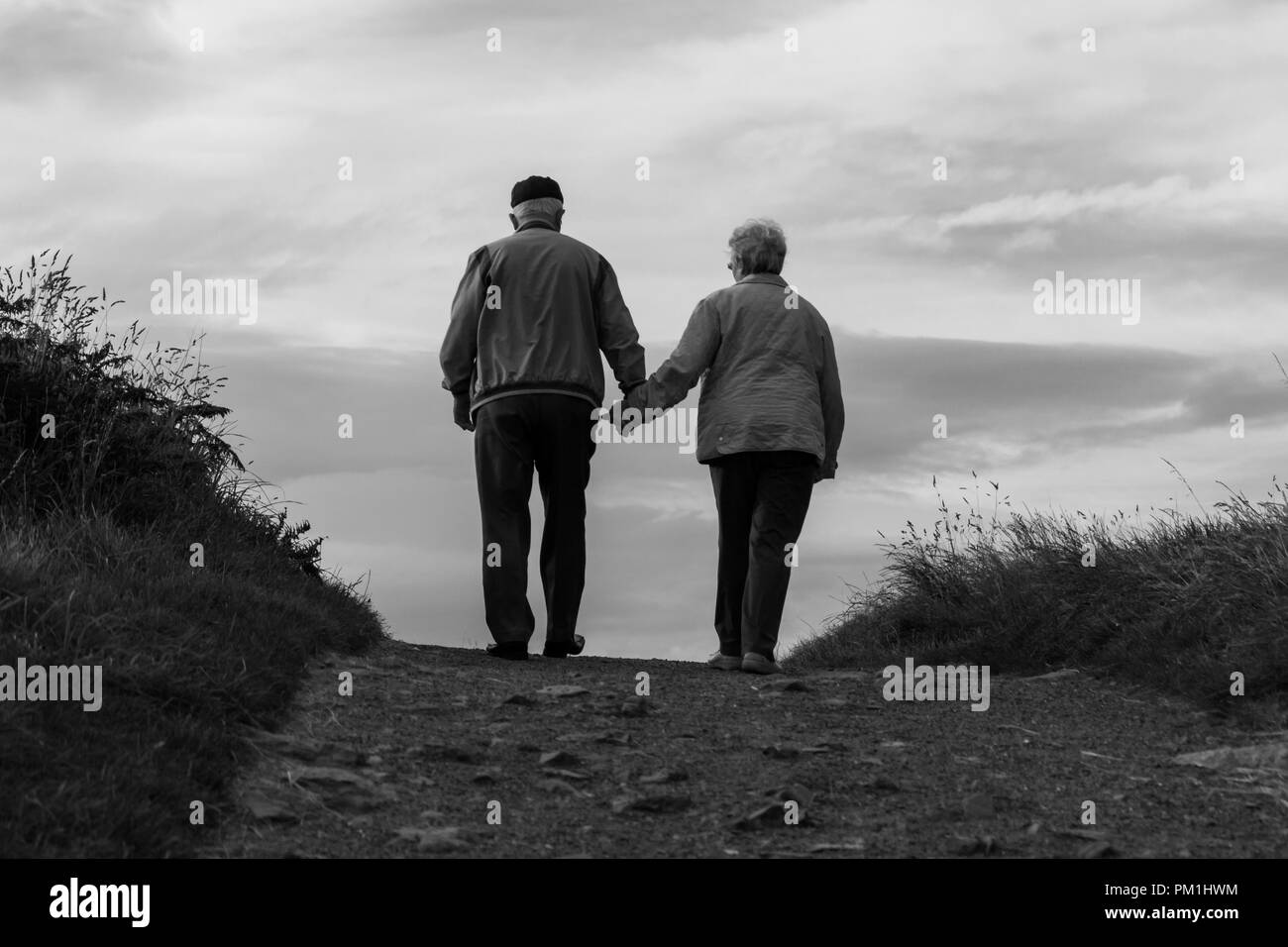 An elderly couple together cresting a hill (black & white) Stock Photo