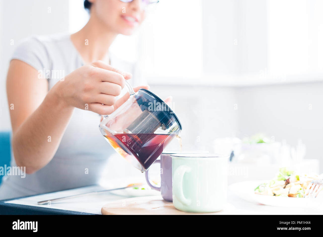 Woman Pouring Tea in Cafe Stock Photo