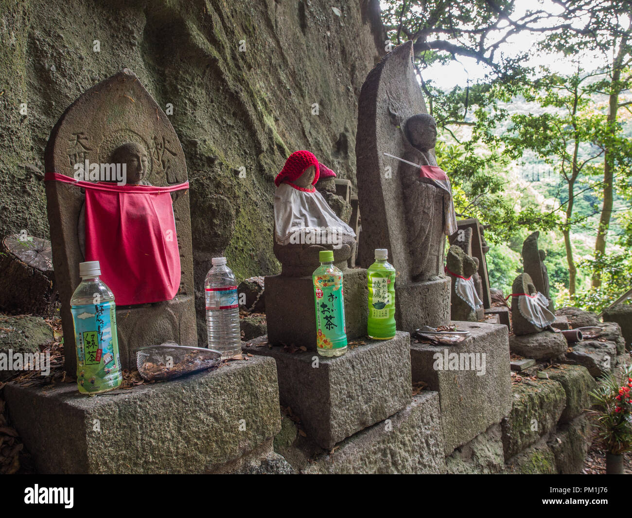 Jizo Bosatsu statues, with bibs, red hat, with offerings of tea,  Iyadaniji temple 71, Shikoku 88 temple pilgrimage, Kagawa, Japan Stock Photo