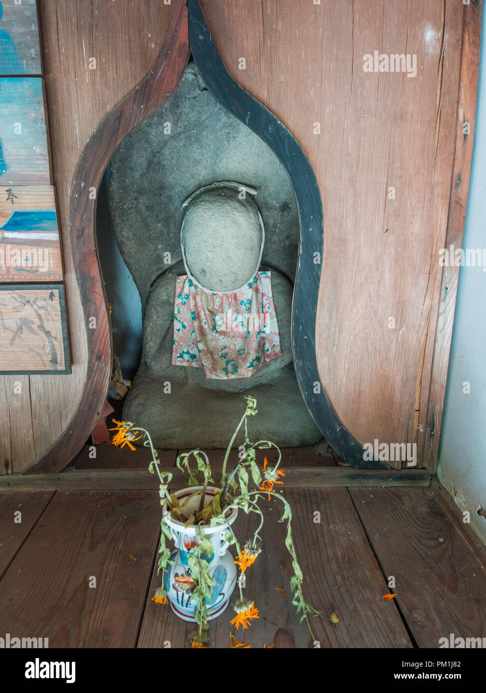 Statue of faceless god with offerings of dead flowers, Kokuzoji temple, Kagawa, Shikoku Stock Photo