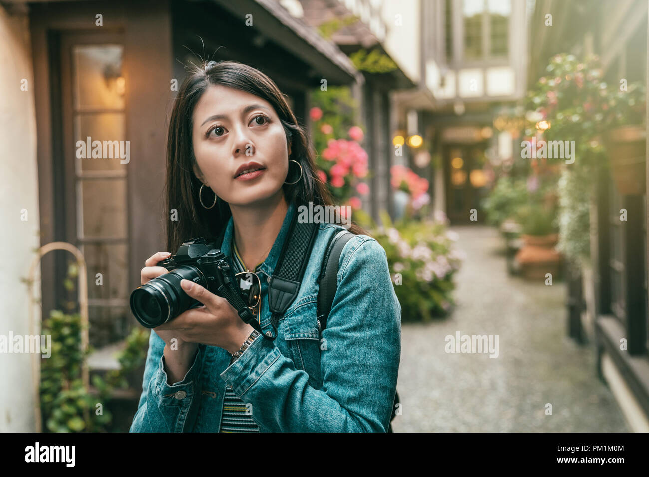 girl taking photos in a alley surrounded by the vintage houses in a town. Stock Photo