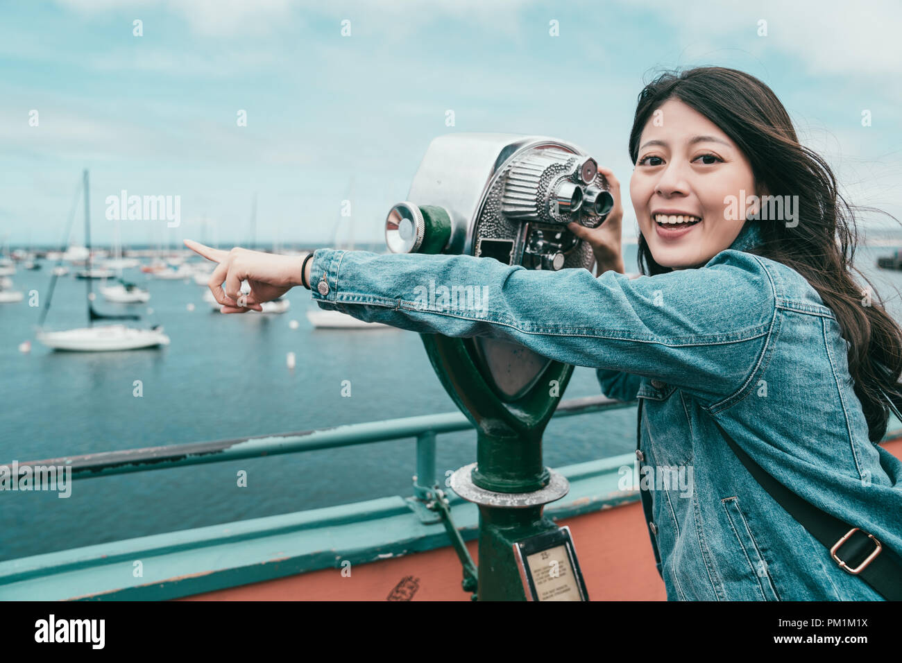 happy beautiful girl pointing at sea while looking through a telescope for finding interesting stuff. Stock Photo