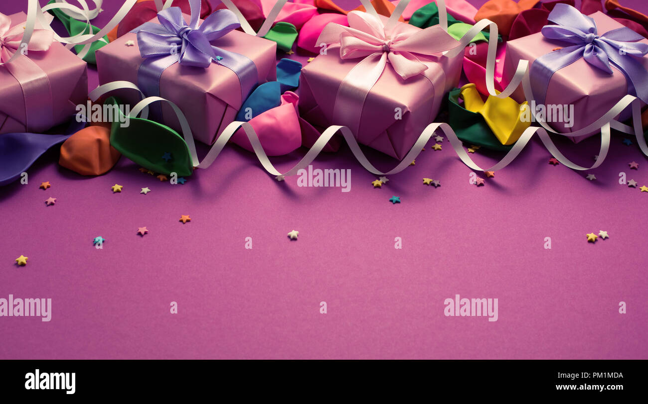 Festive background of purple material colorful balloons streamers confetti four boxes gift. Top view flat lay copy space toning Stock Photo