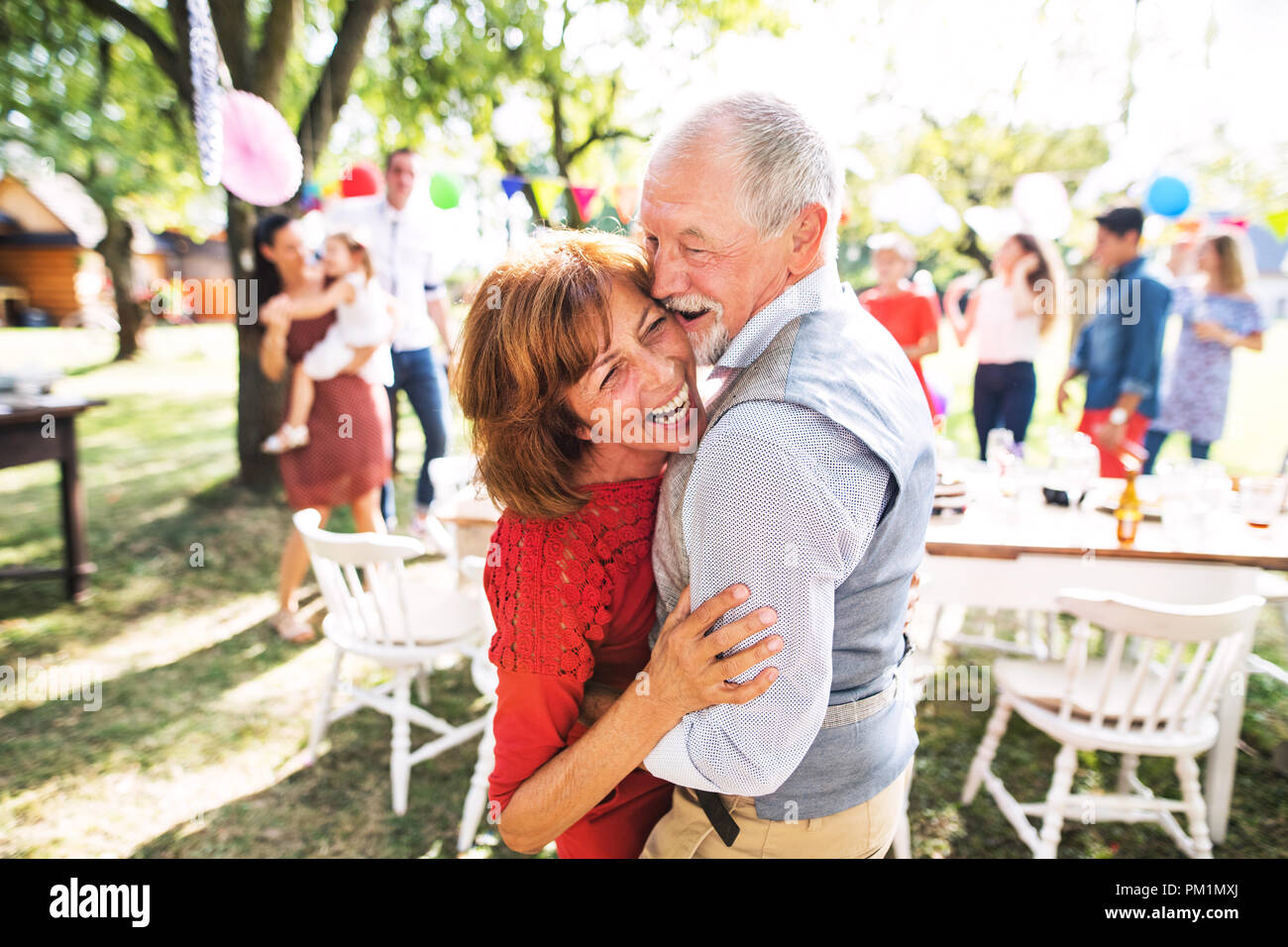 A senior couple dancing on a garden party outside in the backyard. Stock Photo